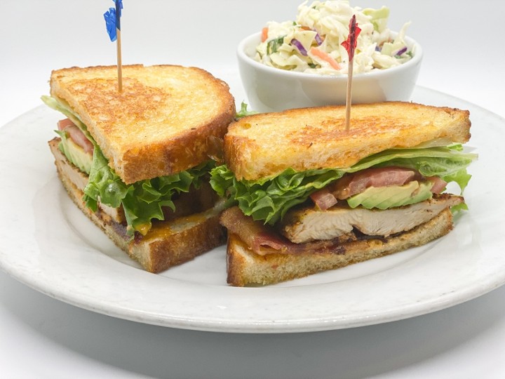 This image depicts our Cajun Club Sandwich that is served with a blackened chicken breast, smoked bacon, avocado, chipotle aioli, lettuce and tomato and is presented with thick-cut sourdough bread slices.